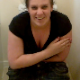 A British girl with a plump bottom is briefly seen sitting on a toilet taking a shit. She mentions the smell, but no pooping sounds can be heard.